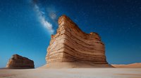 Majestic sandstone rock formation against starry night sky with visible Milky Way galaxy, dramatic desert landscape under moonlight illumination.