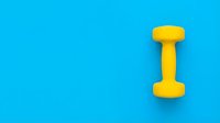 Yellow dumbbell on bright blue background, isolated fitness equipment for gym, workout, and sports design projects.