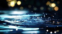 Mesmerizing water ripples with floating droplets creating concentric circles on dark surface, illuminated by soft bokeh lights in turquoise and gold tones.