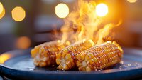 Grilled corn on the cob with melting butter and rising steam on dark plate against blurred warm bokeh lights background, creating cozy atmosphere.