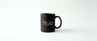 Black ceramic mug with gold Hello lettering isolated on white background, minimalist design for branding, mockup, and product presentation.