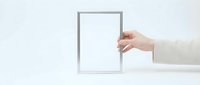Hand holding empty white picture frame on clean minimalist background for mockup design and presentation purposes.
