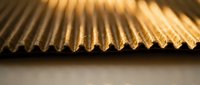Corrugated cardboard edge macro shot showing detailed texture and warm lighting for packaging and shipping industry applications.