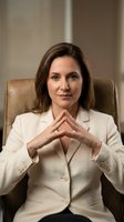 Professional businesswoman in white suit sitting confidently in leather chair with hands steepled, corporate executive portrait for business presentations.