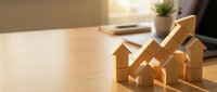 Wooden house models with upward arrow on desk symbolizing real estate growth, property investment success, and housing market trends in warm office setting.