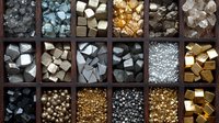 Metallic pyrite, gold, silver and mineral specimens arranged in wooden compartment box display showing variety of colors, textures and geometric shapes.