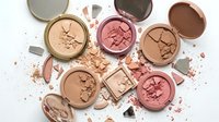 Broken makeup powder compacts with scattered cosmetic debris on white background. Beauty products damage concept for insurance claims.