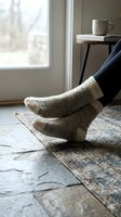 Person wearing cozy wool socks relaxing by window with warm beverage on side table, perfect for lifestyle, comfort, and home relaxation concepts.
