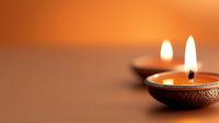 Traditional oil lamps with glowing flames creating warm ambient lighting against soft orange background for meditation and relaxation purposes.
