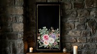 Elegant black chalkboard with floral bouquet of roses and eucalyptus, framed on rustic stone wall with candles, for wedding or event decor.