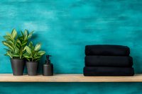 Minimalist spa composition with black folded towels and green plants on wooden shelf against turquoise textured wall, wellness and bathroom decor.