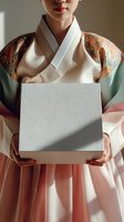 Woman wearing traditional Korean hanbok with ornate patterned jacket holding blank white card for custom text, messaging, or branding purposes.