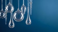 Clear glass ornaments and teardrops hanging against blue gradient background for holiday decoration and festive seasonal design projects.