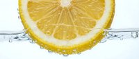 Fresh lemon slice submerged in clear sparkling water with bubbles, vibrant yellow citrus fruit close-up for healthy drink and detox concepts.