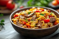 Homemade beef stew with pappardelle pasta, mushrooms, cherry tomatoes and fresh herbs served in rustic brown ceramic bowl on wooden table. Fresh ingredients.