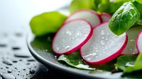 Fresh sliced red radish with water drops and green leaves on black plate, macro food photography for restaurant menu and healthy eating concept.