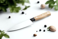 Professional chef knife with wooden handle on white surface, surrounded by fresh herbs, garlic cloves and black peppercorns. Clean minimalist food preparation scene.