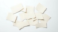 Blank cream paper pieces scattered on white background for notes, reminders and creative projects. Isolated stationery elements for design work.