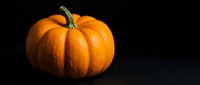 Orange pumpkin with green stem on dark background for autumn harvest decorations, Halloween designs, and seasonal marketing materials.