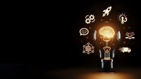 Glowing light bulb with brain inside surrounded by innovation icons on dark background representing creative thinking and business ideas.