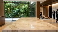 Modern luxury office lobby with marble floors, floor-to-ceiling windows overlooking lush green garden, wooden accents and business professionals.