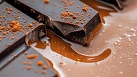 Dark chocolate pieces with melted caramel and cocoa powder on brown background, extreme close up macro food photography for confectionery and dessert advertising.