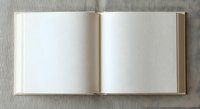 Open blank book with empty white pages on neutral fabric background for writing, journaling, education and creative projects.