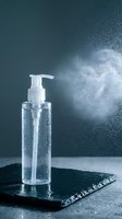 Clear gel cleanser or sanitizer in pump bottle spraying mist against blue background, ideal for skincare, hygiene and cosmetic product marketing.