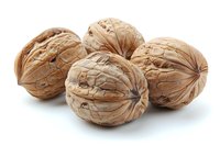Fresh whole walnuts with textured shells isolated on white background, showing natural brown color and distinctive wrinkled surface pattern.