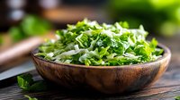 Fresh chopped green cabbage and herbs mixture in wooden bowl on dark rustic table, healthy raw vegetable salad ingredients for cooking.