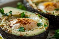 Baked avocado halves with eggs, seasoned with herbs and spices. Healthy breakfast or brunch dish with fresh parsley garnish on rustic wooden surface.