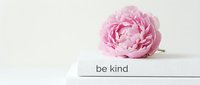 Pink peony flower resting on stacked white books with be kind text, soft light background, minimal elegant style for lifestyle and wellness design.