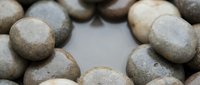 Smooth river stones in natural earth tones arranged on white background, perfect for spa wellness meditation zen garden landscaping design projects.