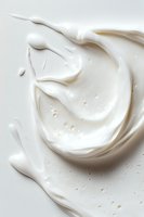 Swirling white cream texture with smooth glossy surface and delicate ripples creates abstract pattern on light background, suitable for cosmetic and food advertising.