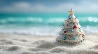 Festive sand Christmas tree with star topper and colorful ornaments on tropical beach with turquoise ocean backdrop.