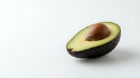 Fresh ripe avocado half with pit on clean white background, healthy organic fruit for cooking, nutrition and diet concepts.