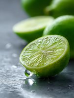 Fresh cut lime with water drops on dark stone background, macro shot showing detailed citrus flesh texture and vibrant green color. Suitable for food and beverage marketing.