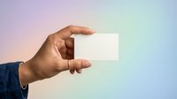 Hand holding blank white business card against soft gradient background of pink, purple, and blue tones. Suitable for branding, corporate identity, and marketing mockups.