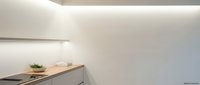 Modern minimalist kitchen interior with clean white cabinets, wooden countertop and subtle LED lighting creating warm ambiance for contemporary home design.