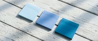 Three blue gradient ceramic tiles arranged on weathered wooden planks showcasing color transition from light to dark blue for interior design projects.