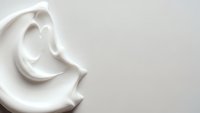 White cream swirl on neutral background with smooth texture and elegant curves for skincare and cosmetic product design applications.
