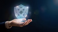 Hand holding glowing digital shield symbol representing cybersecurity, data protection, and network safety for technology and business concepts.