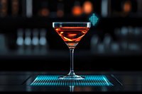 Elegant cocktail glass with amber liquid on glowing blue bar mat against dark background with bokeh lights, modern mixology and nightlife atmosphere.