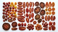Flat lay arrangement of various roasted nuts including pecans, almonds and walnuts on white background, suitable for food photography, nutrition content and culinary design projects.