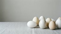 Fresh organic eggs arranged on marble surface against neutral background for cooking and baking projects.