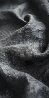 Monochrome close-up of draped linen fabric with fine woven texture and soft folds, showcasing natural material details for textile, fashion, and interior design projects.