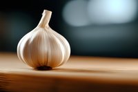 Fresh whole garlic bulb on wooden cutting board in modern kitchen setting for cooking and culinary preparation.
