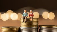 Elderly couple miniature figures sitting on stacks of golden coins representing retirement savings and financial planning for senior years.