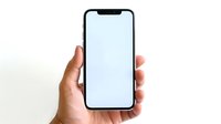 Modern smartphone with blank white screen held in hand against white background, mockup ready for app or website presentation.