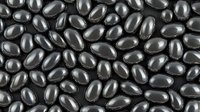 Shiny black oval pills or supplements scattered across surface creating abstract pharmaceutical pattern with glossy reflective texture. Medical background.